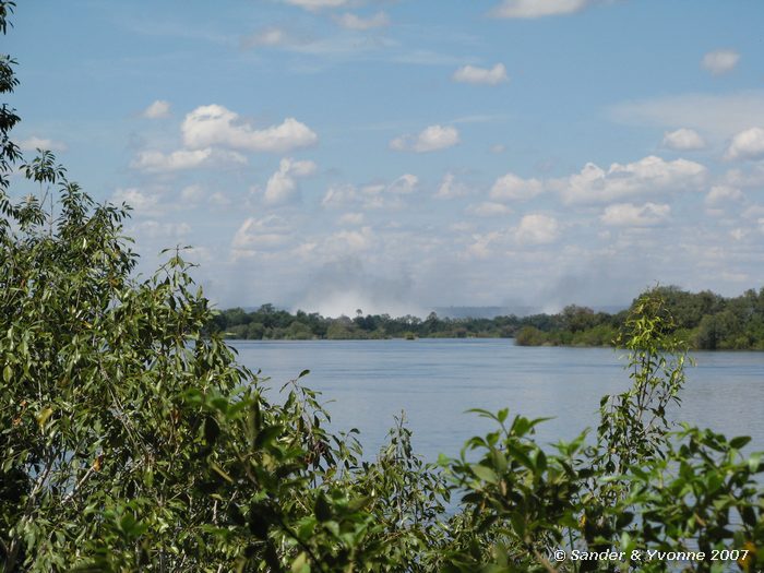 De watersluier van de Victoria Falls in de verte, gezien vanaf de Waterfront campsite